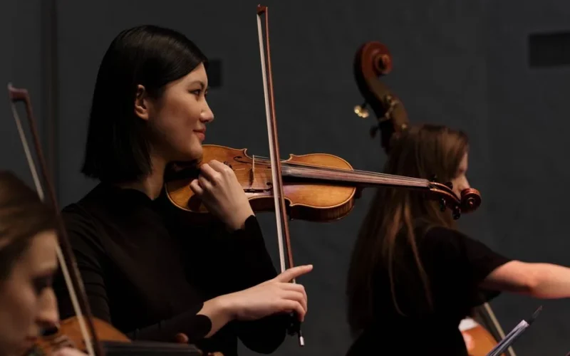 Asian female violinist performing on stage during a live concert.