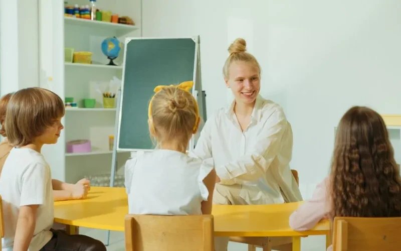 Teacher engaging with preschool children in a colorful classroom setting.