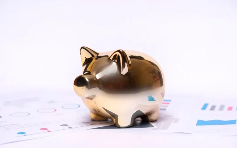 Close-up of a golden piggy bank on financial documents, symbolizing savings and investment.