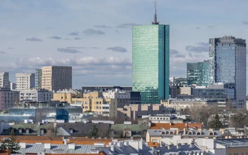 A sunny daytime cityscape of Warsaw's modern skyline with high-rise buildings and distinctive architecture.