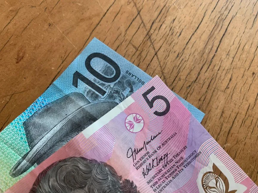 Close-up of Australian 5 and 10 dollar notes on a wooden background.