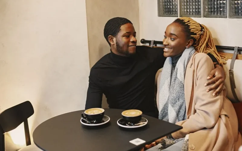 Warm and cozy moment of a couple sharing smiles over coffee in a cafe setting.