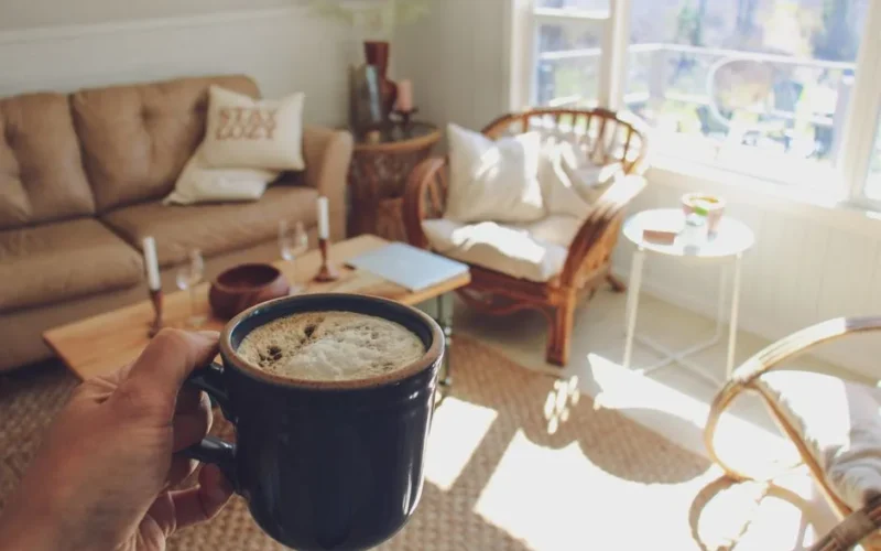 Enjoy a peaceful moment with coffee in a bright, cozy living room with warm sunlight.