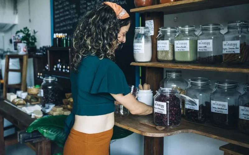 A woman selecting organic items in a refillable jar at an eco-friendly grocery store.