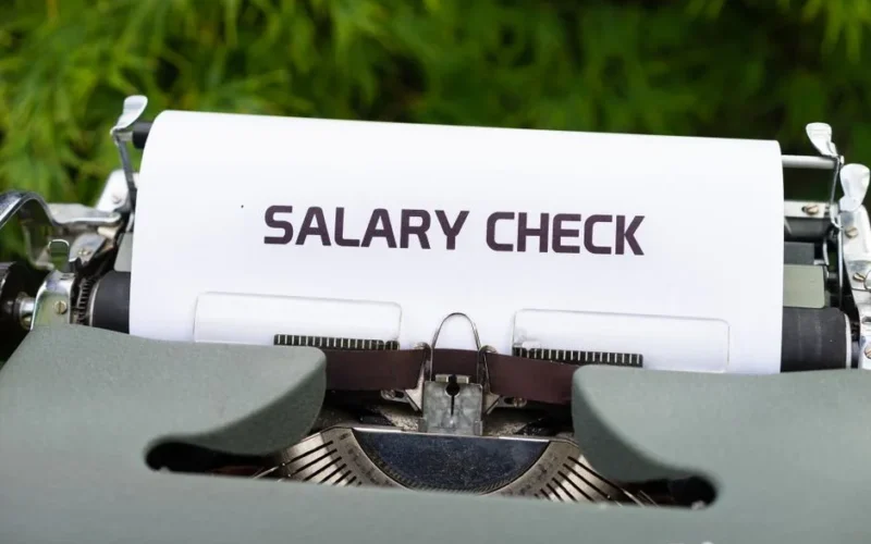 Close-up of a vintage typewriter typing 'Salary Check' on paper, symbolizing payroll and finance.