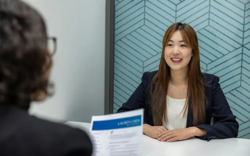 Young woman in a business meeting with an interviewer, showcasing confidence and professionalism.